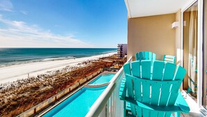 Un balcon avec vue sur une plage et une piscine.