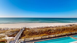 Une vue sur la plage, avec une piscine et une terrasse en bois.