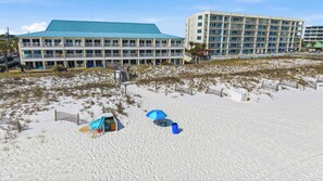 Ein Strandhotel mit mehreren Balkonen, einem Poolbereich und einem Sandstrand.