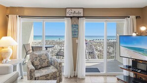 A room with a TV, a sofa, a lamp, and a view of the beach. - Beautiful beachfront condo with million-dollar views with Seasonal Beach Service and Beach Access (Fort Walton Beach)