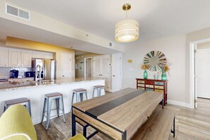 Eine moderne Küche mit einer zentralen Kochinsel, Barhocker und einem langen Holztisch.