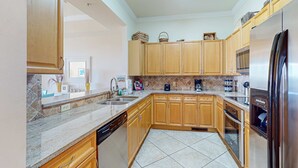 A modern kitchen with wooden cabinets, a stainless steel refrigerator, and a dishwasher. - Stylish townhouse condo near the beach with full kitchen, WiFi, and shared pool (Santa Rosa Beach)