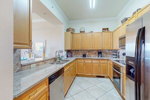 A modern kitchen with wooden cabinets, a stainless steel refrigerator, and a dishwasher. - Stylish townhouse condo near the beach with full kitchen, WiFi, and shared pool (Santa Rosa Beach)
