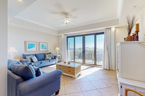 Ein geräumiges Wohnzimmer mit großem Fenster, Deckenventilator, einer Couch, einem Couchtisch und einem Schrank.
