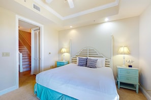 A bedroom with a large bed, two bedside tables with lamps, a wooden headboard, and a staircase leading to a closet. - Stylish townhouse condo near the beach with full kitchen, WiFi, and shared pool (Santa Rosa Beach)