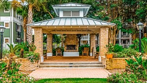 A covered patio with brick pillars, a fireplace, and outdoor seating. - Fourth-floor studio with shared pool, fast WiFi, washer&dryer, & central AC (Miramar Beach)