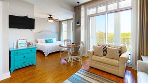 A bedroom with a bed, a desk, and a chair. There is a window with curtains and a view of greenery outside. - Fourth-floor studio with shared pool, fast WiFi, washer&dryer, & central AC (Miramar Beach)