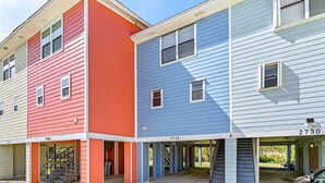 A row of three-story townhouses with external staircases and numbered addresses. - Dog-friendly townhome with private deck, charming interior, washer&dryer & AC (Gulf Breeze)