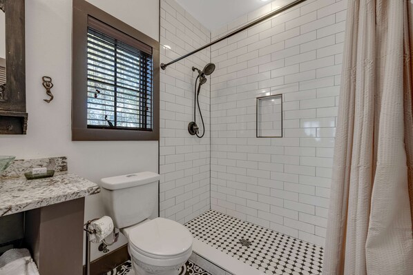 Une salle de bain comprenant des toilettes, un lavabo et un espace douche.
