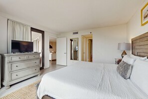 A bedroom with a bed, dresser, television, and a lamp. - Beautiful beachfront condo with pool, beach tram, tennis, golf, & on-site dining (Miramar Beach)