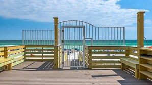 A wooden boardwalk leading to a beach with a metal gate. - Beautiful beachfront condo with pool, beach tram, tennis, golf, & on-site dining (Miramar Beach)
