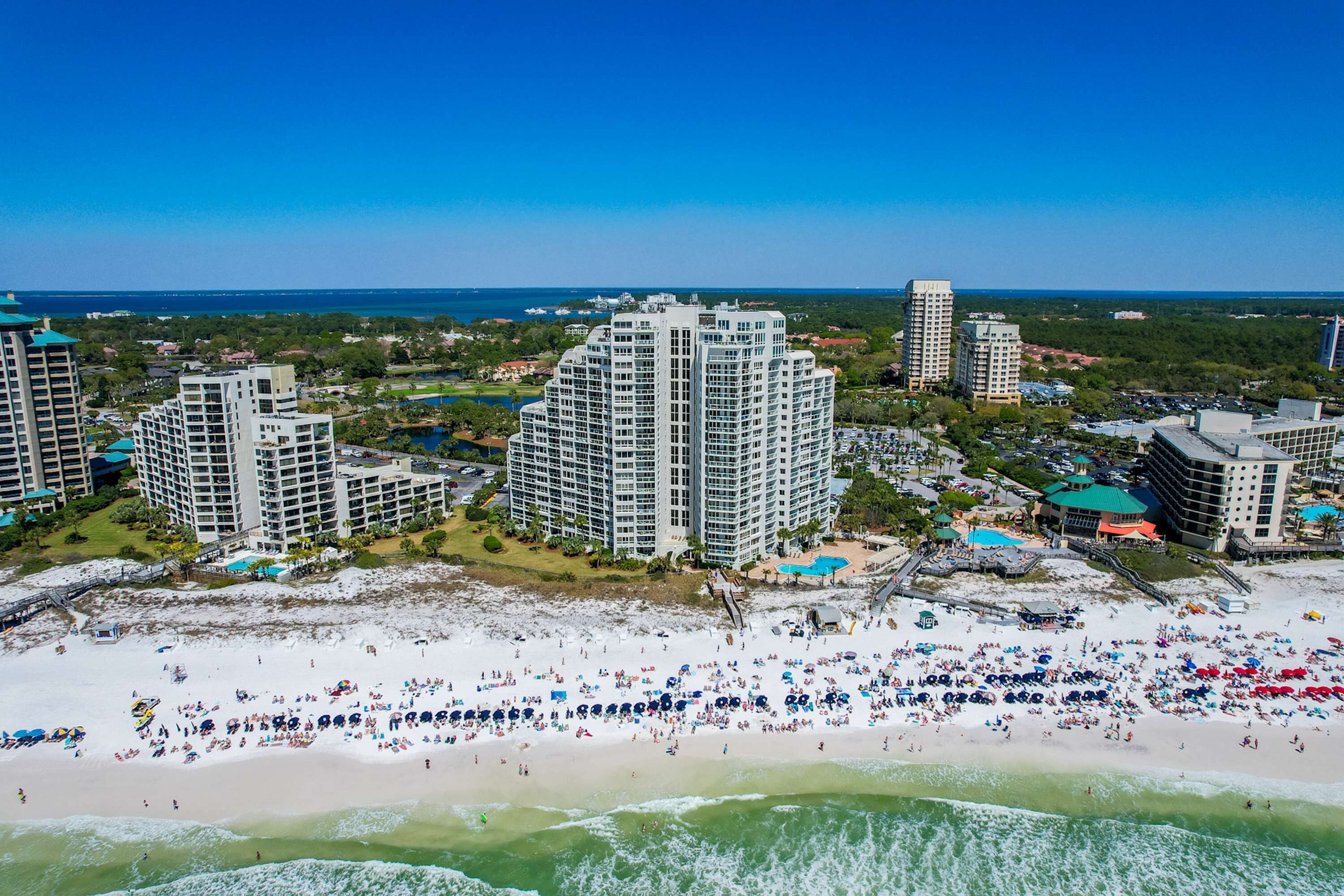 A coastal resort area with high-rise hotels, a sandy beach, and a view of the ocean.