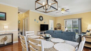 Un salon comprenant une table à manger, des chaises, un canapé, un téléviseur et un ventilateur de plafond.
