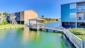 Ein Wohnhaus am Wasserufer mit Anlegesteg, überdachter Sitzgelegenheit und mehreren Balkonen.