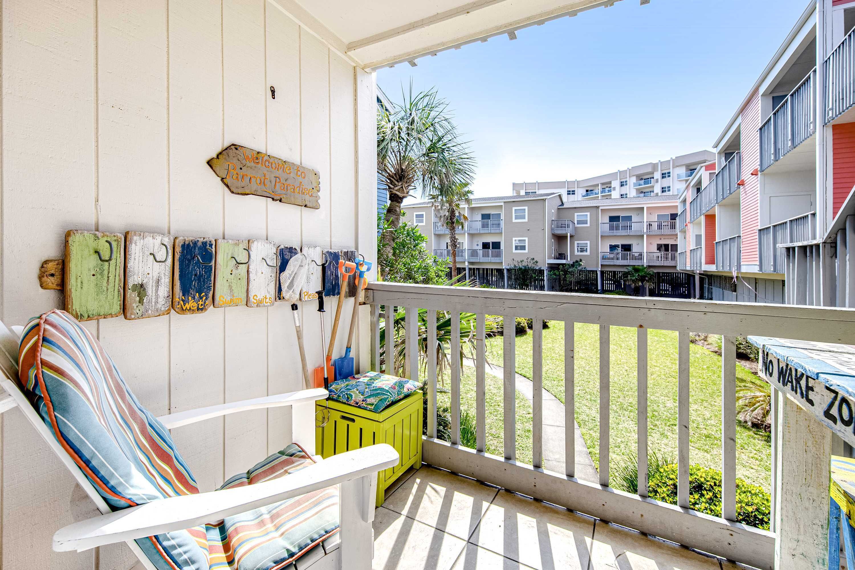 A balcony with a white railing, a green bench, and a striped cushion. A sign reads "Welcome to Paradise."