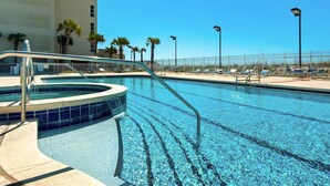 Una piscina con hidromasaje, sillas de descanso y una valla.