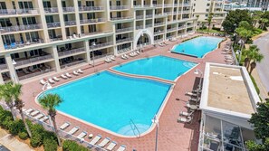 Et hotel med to swimmingpools, flere balkoner og liggestole.