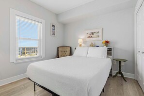 A bedroom with a bed, a window with blinds, a chair, a table with a lamp, and a picture on the wall. - Gorgeous Gulf View Condo with Beach Access and Resort Pool (Miramar Beach)