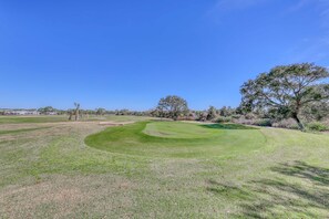 A golf course with a well-maintained green, trees, and a clear blue sky. - Gorgeous gulfview condo with spacious balcony, shared pool, hot tub& beach access (Miramar Beach)