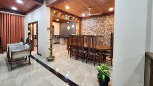 Uma ampla área de jantar com uma mesa e cadeiras de madeira, um painel decorativo e um ventilador de teto.