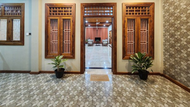 Um corredor com piso estampado, portas de madeira com painéis de vidro e plantas em vasos.