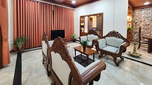 Uma sala de estar ampla com móveis de madeira, televisão de tela plana e ventilador de teto.