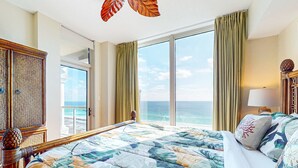A hotel room with a large bed, a view of the ocean, and a balcony. - Gorgeous Resort Condo with Gulf Views, Shared Hot Tub, Pools, & Gym (Pensacola Beach)
