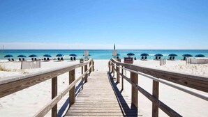A wooden boardwalk leading to a beach with umbrellas and lounge chairs. - Gorgeous Resort Condo with Gulf Views, Shared Hot Tub, Pools, & Gym (Pensacola Beach)