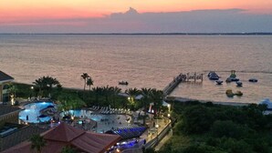 A resort with a large pool area, a pier extending into the water, and a sunset in the background. - Gorgeous Resort Condo with Gulf Views, Shared Hot Tub, Pools, & Gym (Pensacola Beach)