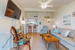 A living room with a sofa, a wooden coffee table, and a TV mounted on the wall. - Comfy Coastal Condo w/ Gorgeous Bay Views & Nearby Beach Access (Pensacola Beach)