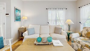 Ein Wohnzimmer mit einem beigen Sofa, einem Holztisch mit Dekoration und zwei Lampen.