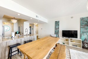 Eine moderne Küche mit Esstisch aus Holz, Barhocker und einem eingebauten Fernseher.