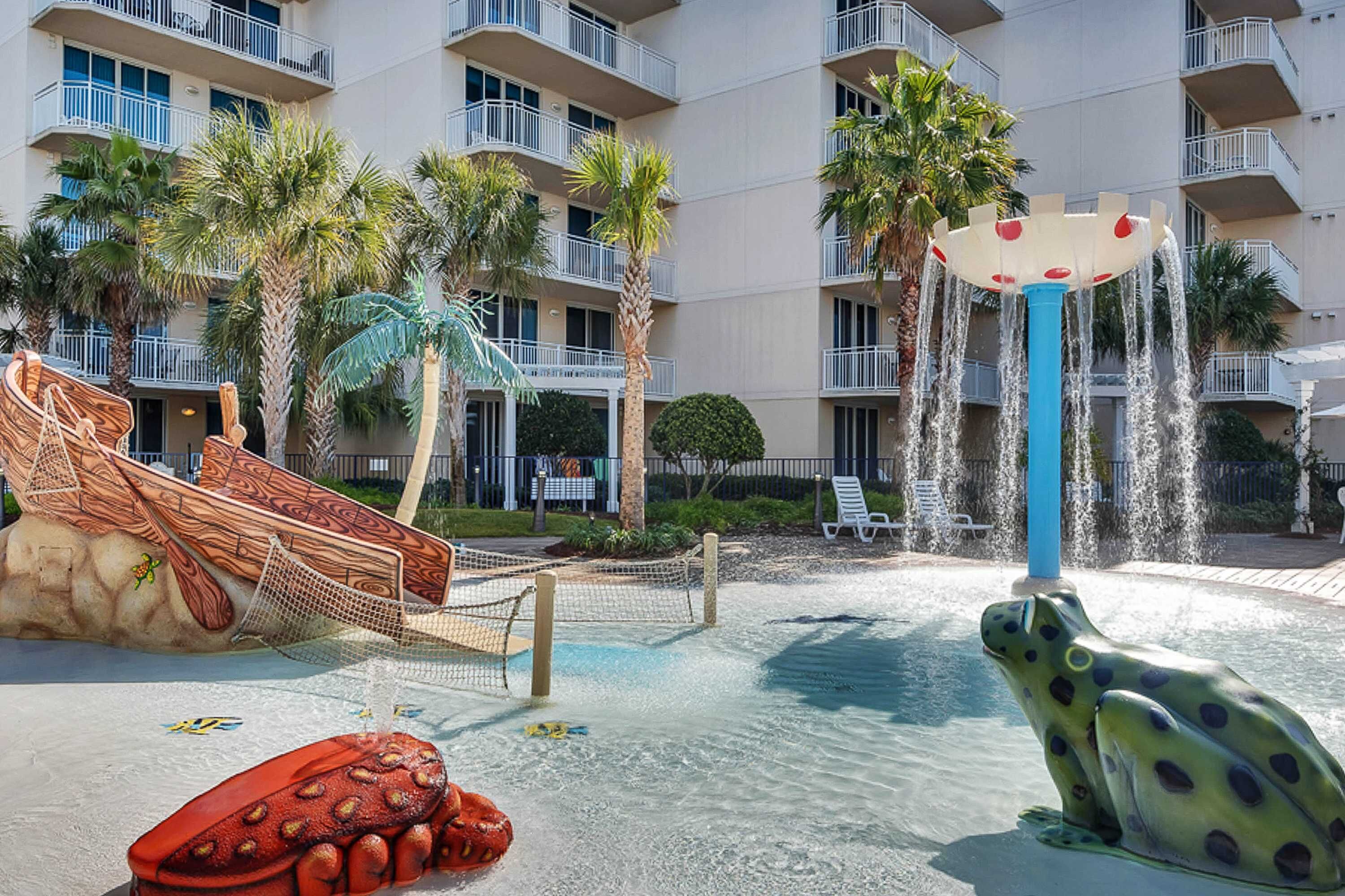 Un parc aquatique avec un toboggan, une statue de grenouille et une fontaine.