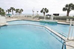 Ein Swimmingpool mit weißem Zaun, Palmen und Blick auf den Ozean.