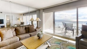 Een moderne hotelkamer met een groot balkon, een bank, een bijzettafeltje en een televisie.