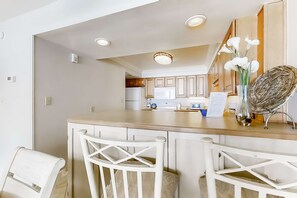 A kitchen with white cabinets, a wooden countertop, and a vase with flowers. - Spacious beachfront condo on second floor with balcony, beach views & pool (Miramar Beach)