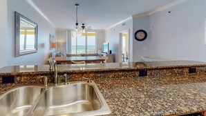Una cocina moderna con encimeras de granito, lavamanos de acero inoxidable y una isla central.