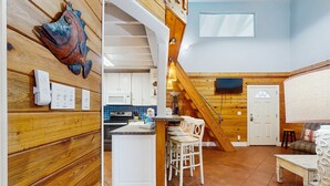 Une cuisine spacieuse agrémentée d’éléments en bois, un coin repas avec un plafond haut et un espace salon confortable.