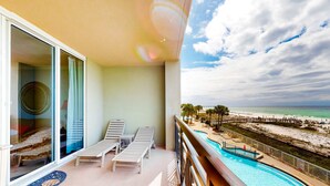 Un balcón con piscina, sillas de descanso y vistas a la playa.