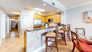 Una cocina con armarios de madera, una isla central y un comedor con sillas.