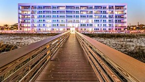A multi-story hotel with a central entrance and a wooden walkway leading to it. - Blu 301 - Third-floor, Gulf-view condo with pool and hot tub access, central AC, & W&D (Fort Walton Beach)