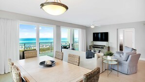 A modern living room with a dining area, large windows, and a view of the ocean. - Blu 301 - Third-floor, Gulf-view condo with pool and hot tub access, central AC, & W&D (Fort Walton Beach)