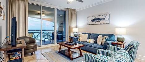 A living room with a sofa, armchairs, a coffee table, a TV on a stand, and a ceiling fan.