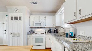 A modern kitchen with white cabinets, a microwave, stove, and a sink. - Cozy sound side condo with shared pool, Close to shopping and beach (Fort Walton Beach)