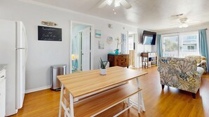 A spacious living area with a wooden table, a sofa, ceiling fans, and a view of the outside. - Cozy sound side condo with shared pool, Close to shopping and beach (Fort Walton Beach)