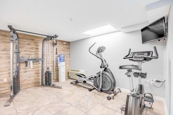 Un gimnasio con bicicleta estática, elíptica y máquina de pesas.