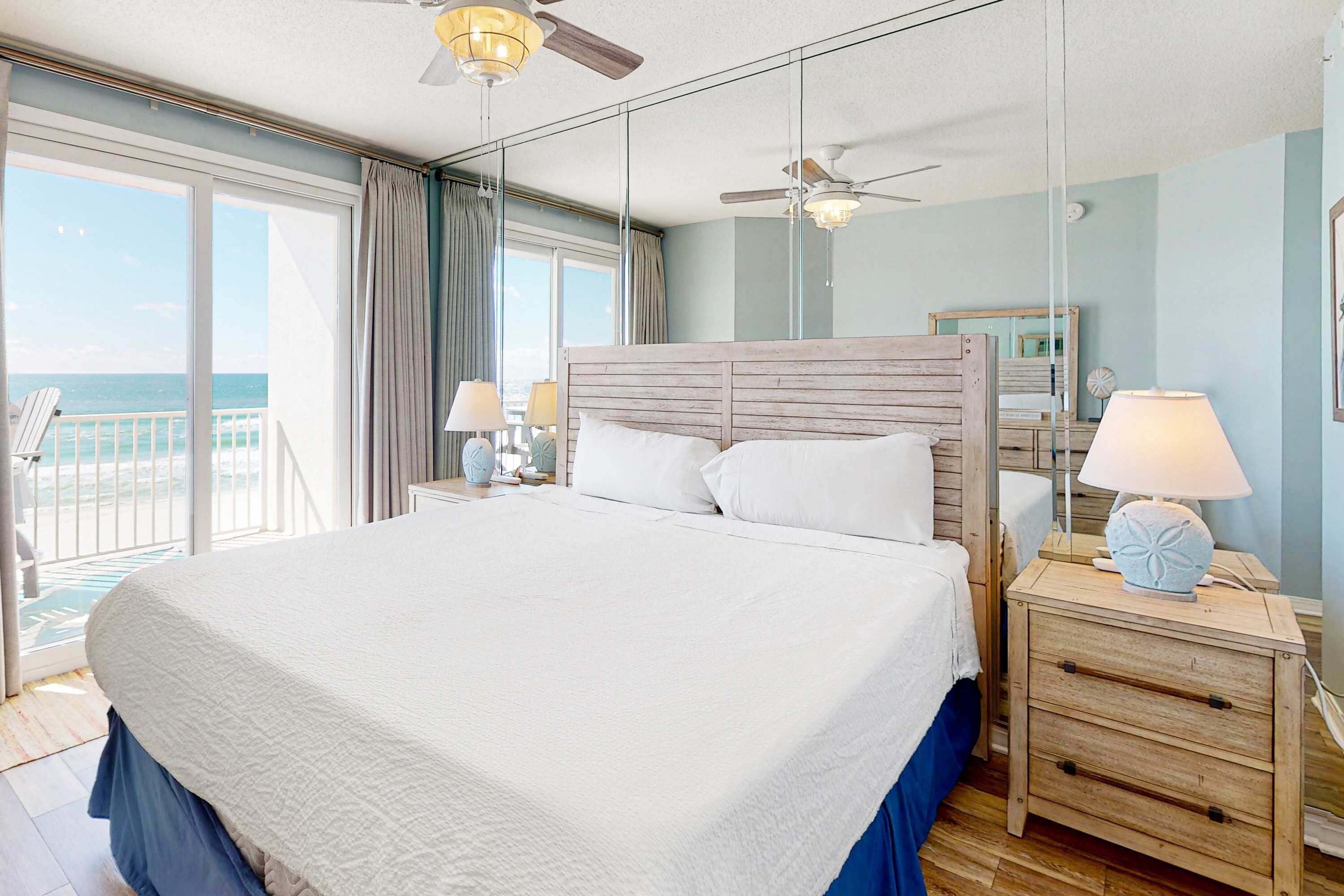 Una cama grande con cabecera de madera en una habitación con vistas al balcón.