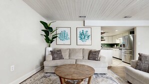 Ein Wohnzimmer mit einer Couch, einem Couchtisch und zwei gerahmten Kunstwerken mit Korallenmotiven an der Wand.