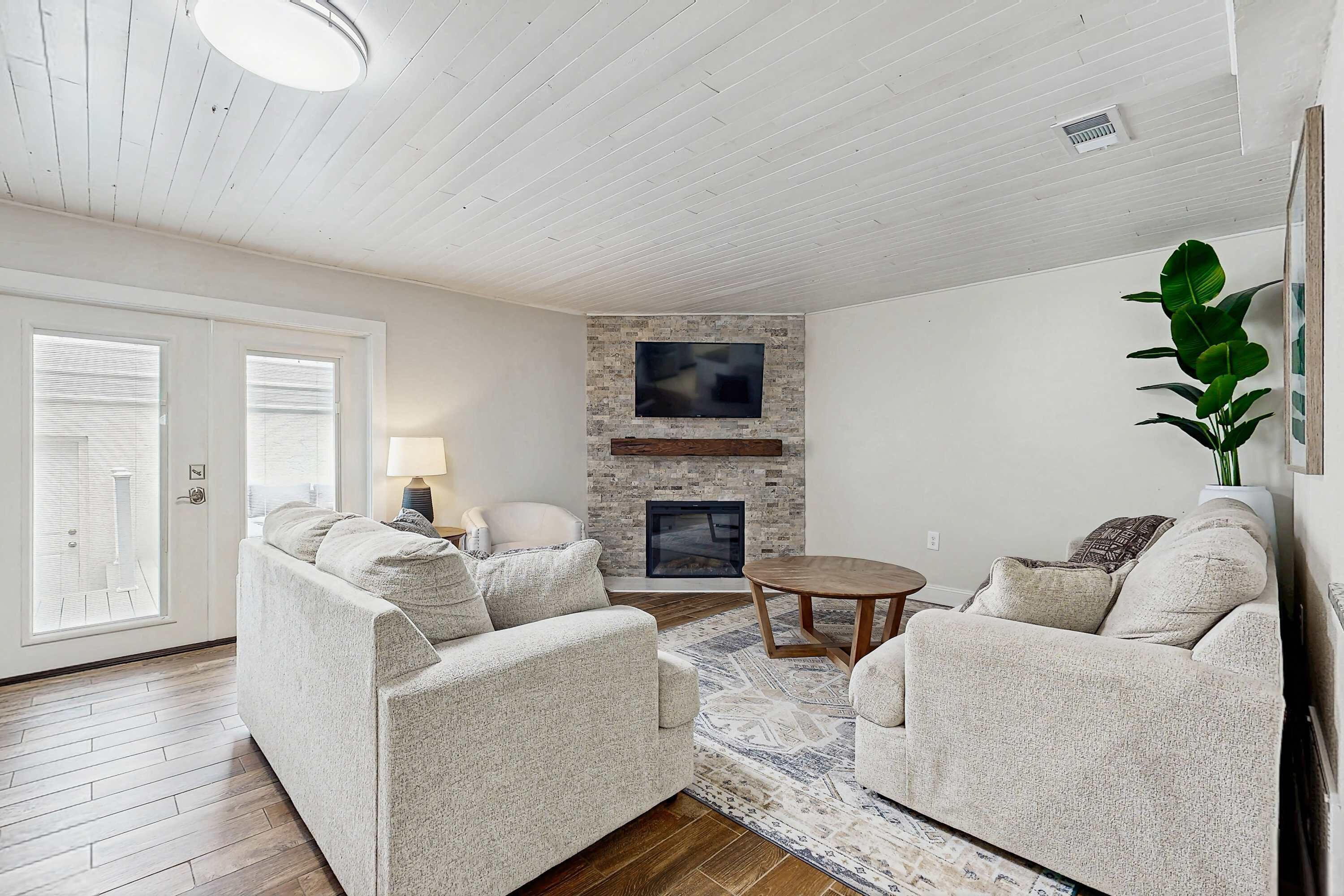 A living room with a fireplace, two sofas, a coffee table, and a large window.