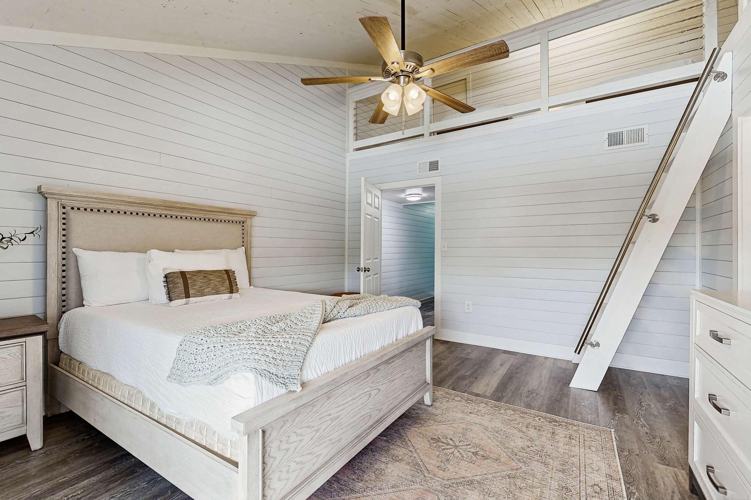 A bedroom with a wooden bed, a ceiling fan, a nightstand, and a dresser.